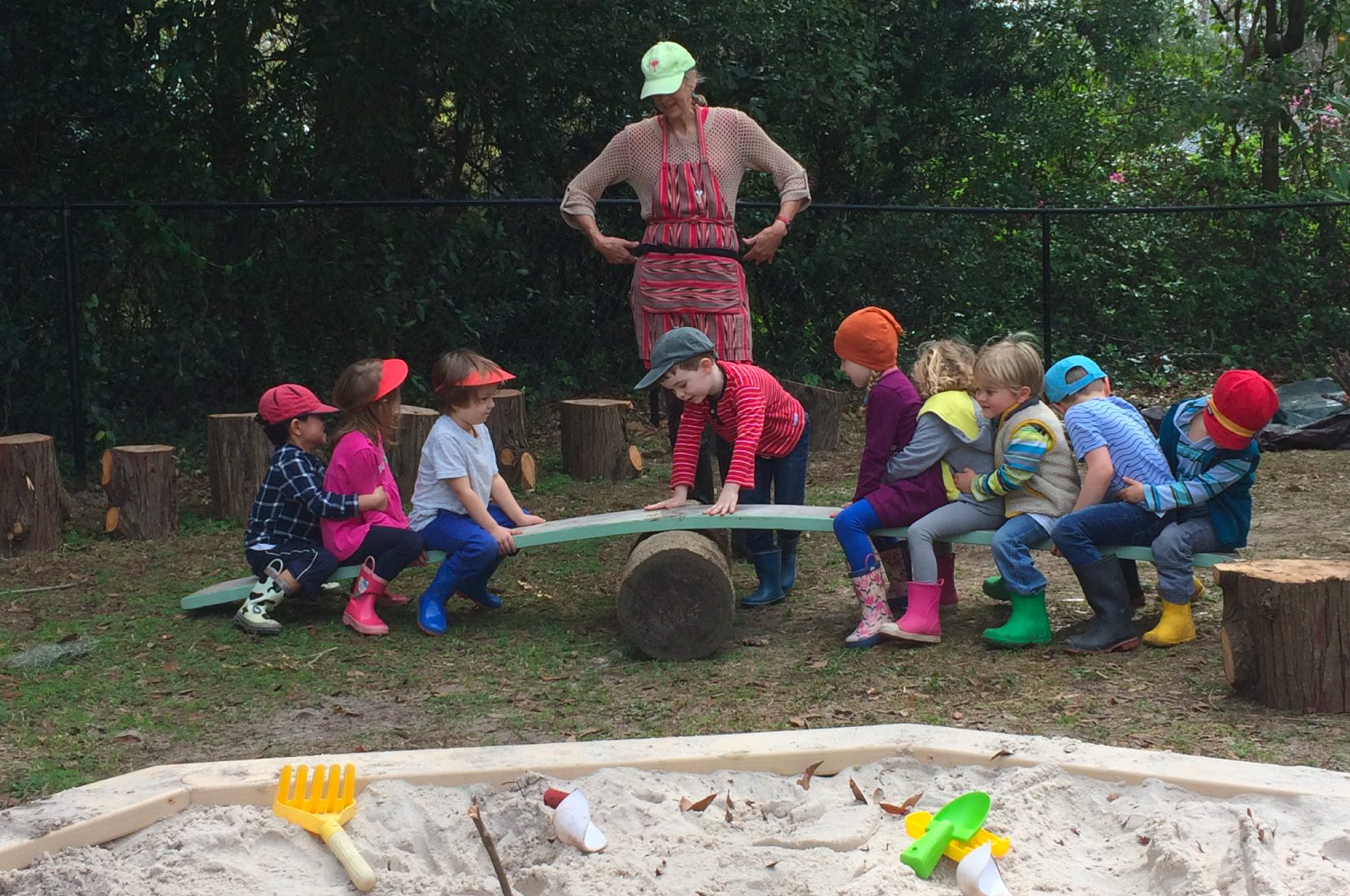 Waldorf kindergarten children and teacher playing on seesaw outside